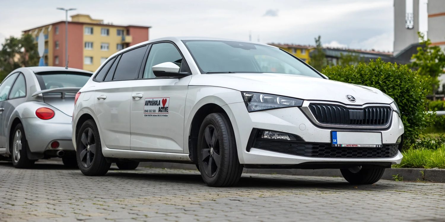 Biele tréningové auto s nápisom Autoškola Active zaparkované v Bratislave na Slovensku s kontaktnými údajmi na dverách